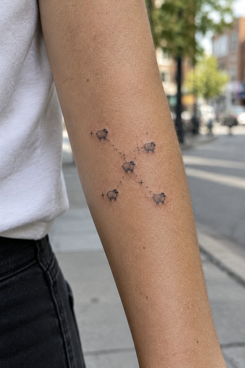 Arm in white shirt with sheep constellation tattoo of dotted lines and stars