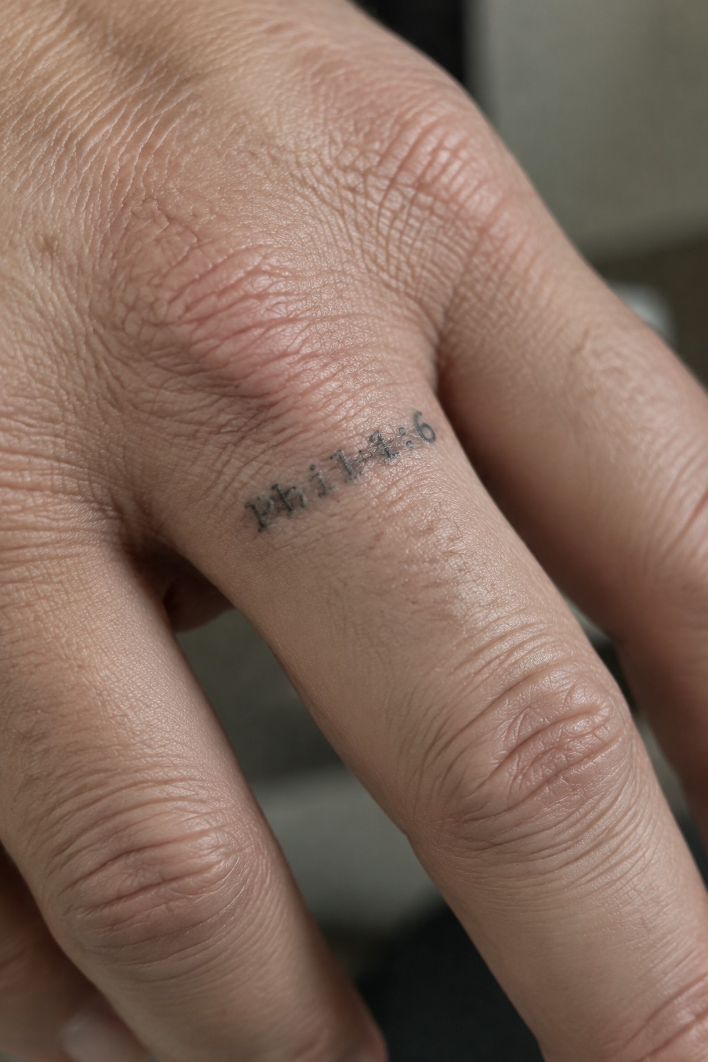 Close-up of finger skin with black tattoo reading
