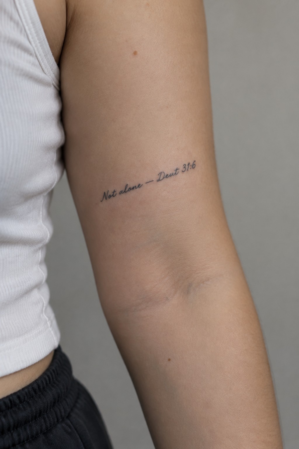 Tattooed arm with cursive text 