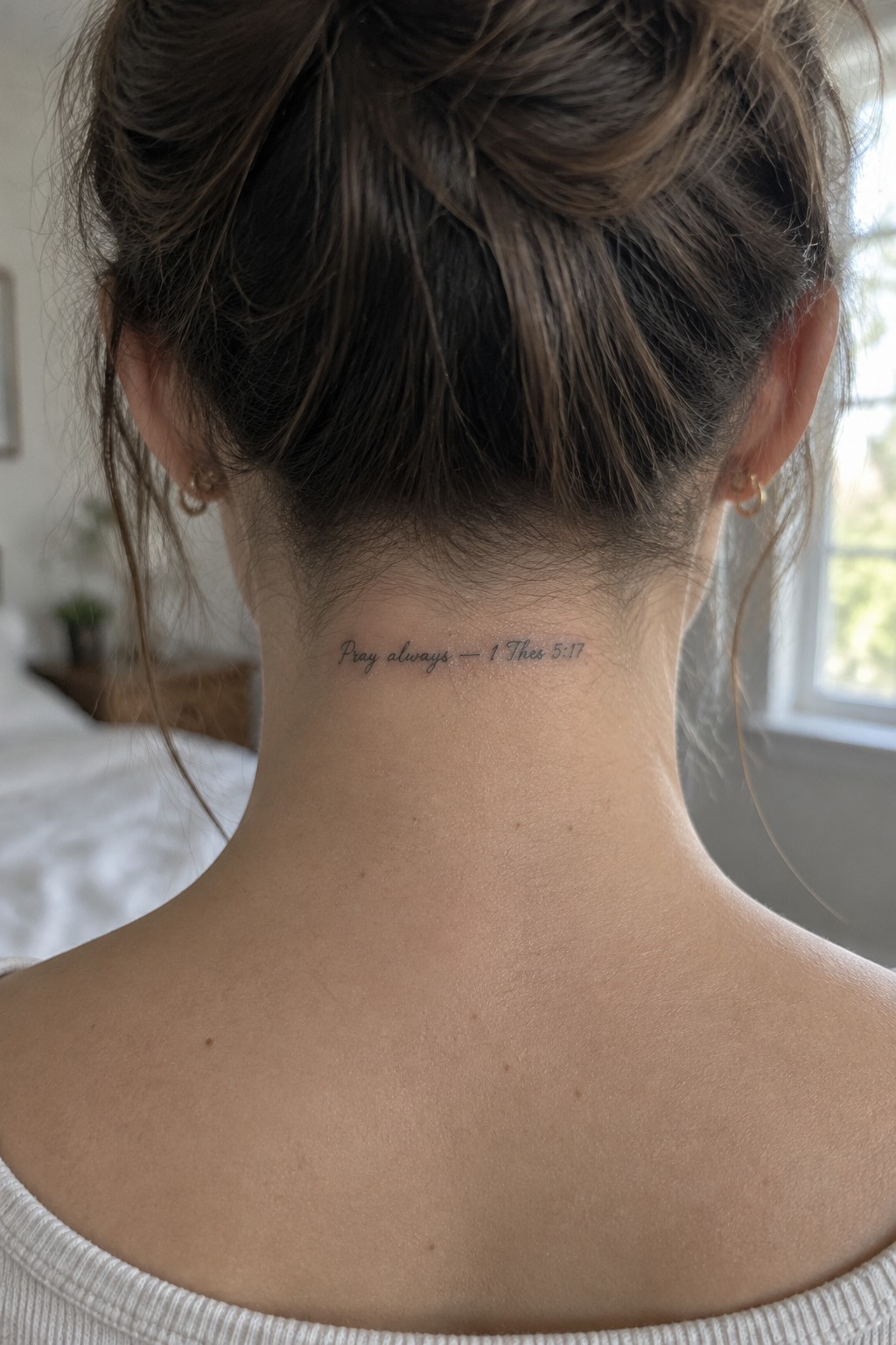 Close up of a small cursive script tattoo on the nape of the neck reading 