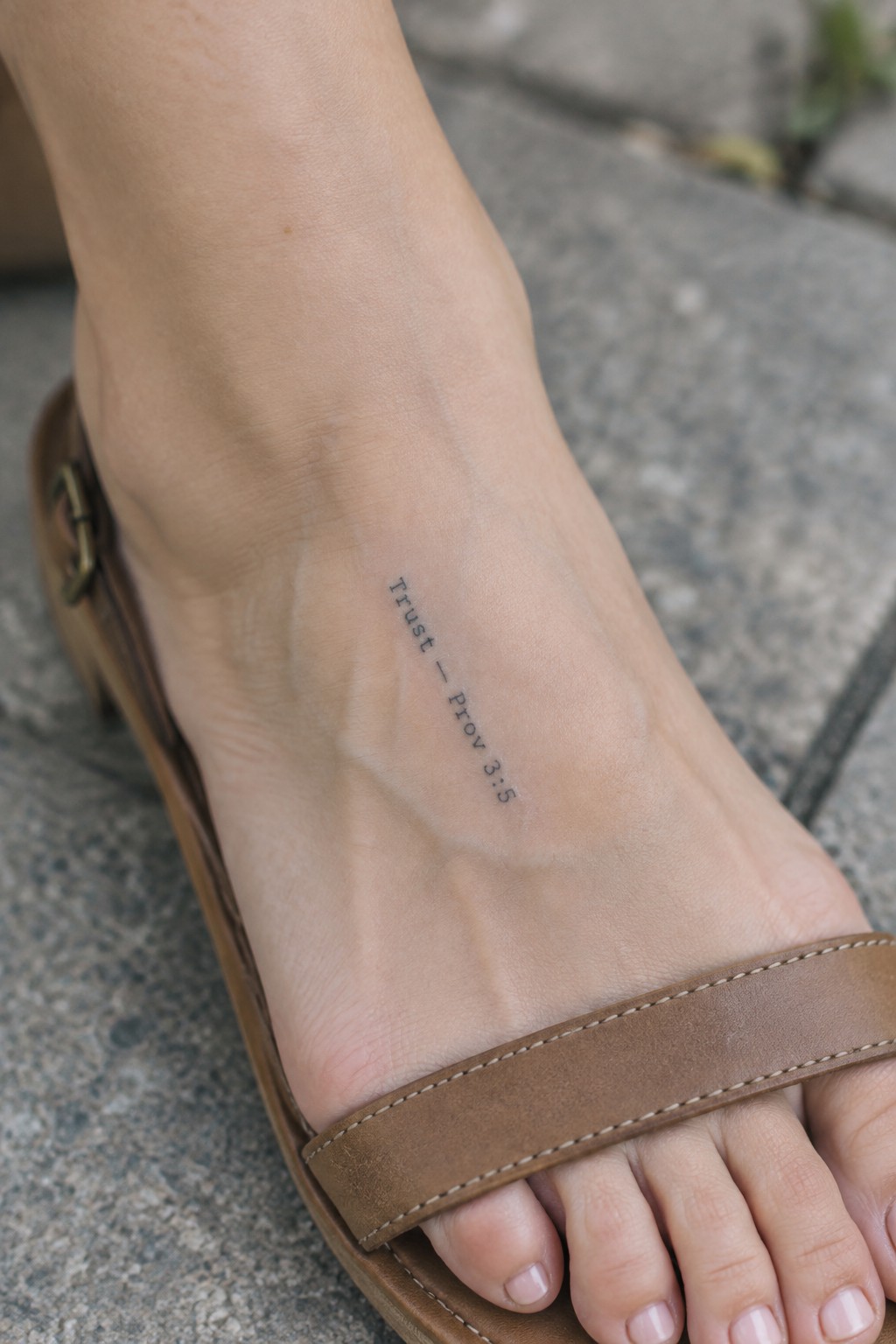 Close-up of light-skinned foot in brown leather sandal with 