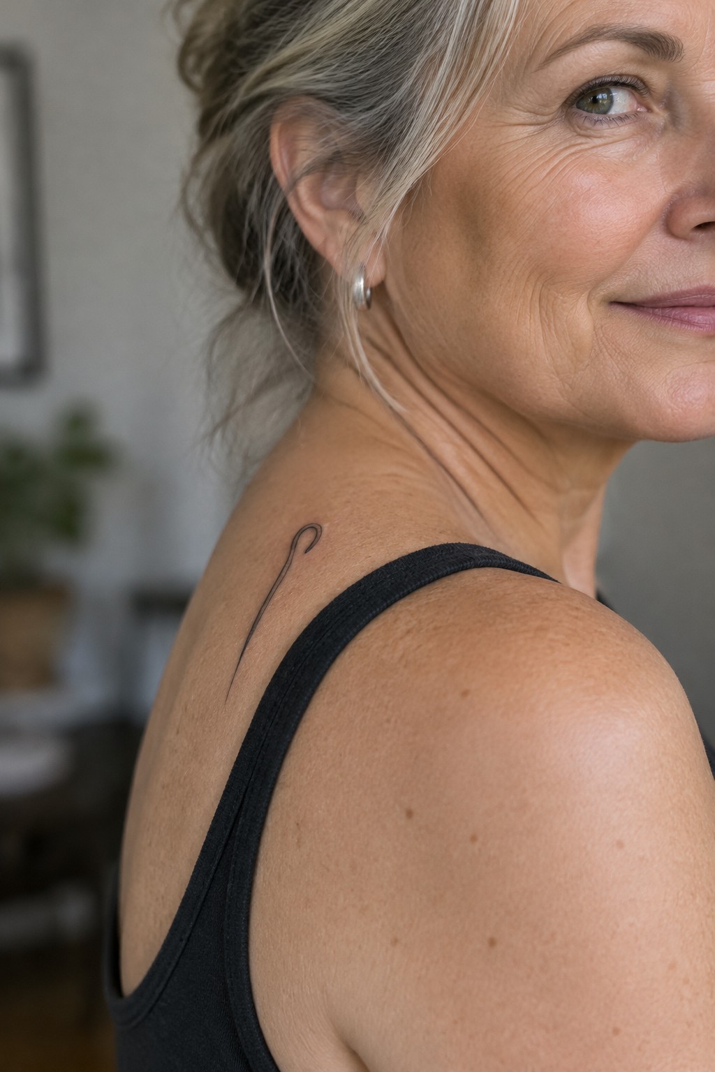 Blonde woman in black tank top with hook tattoo on shoulder