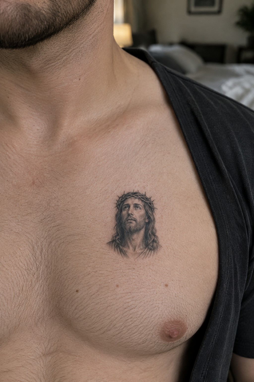 Realistic black and grey tattoo of Jesus Christ with crown of thorns on a man's upper chest.