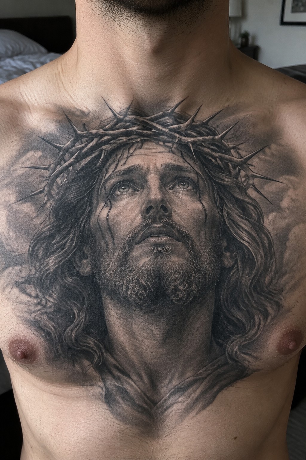 Black and gray realistic tattoo of Jesus with crown of thorns covering a man's upper chest