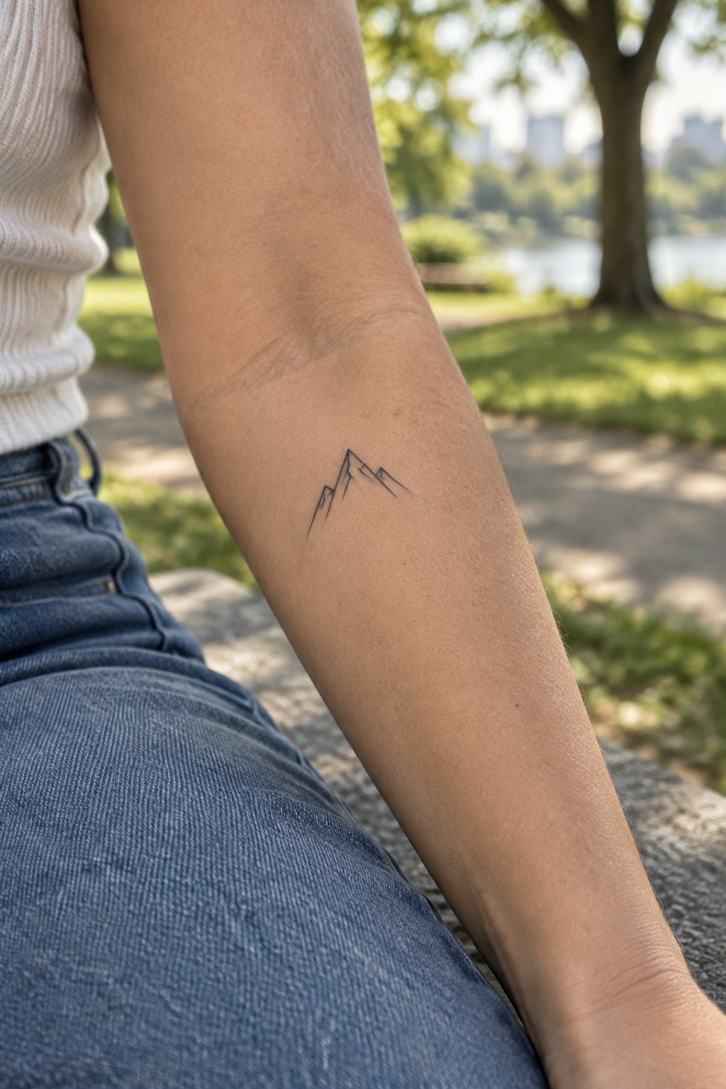 Small fine-line outline of mountain peaks tattooed on the inner forearm.