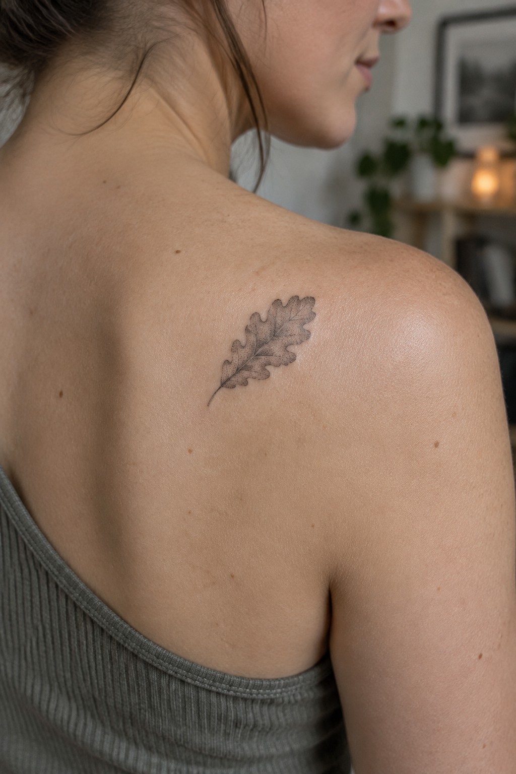 Small shaded oak leaf tattoo on a woman’s upper shoulder.