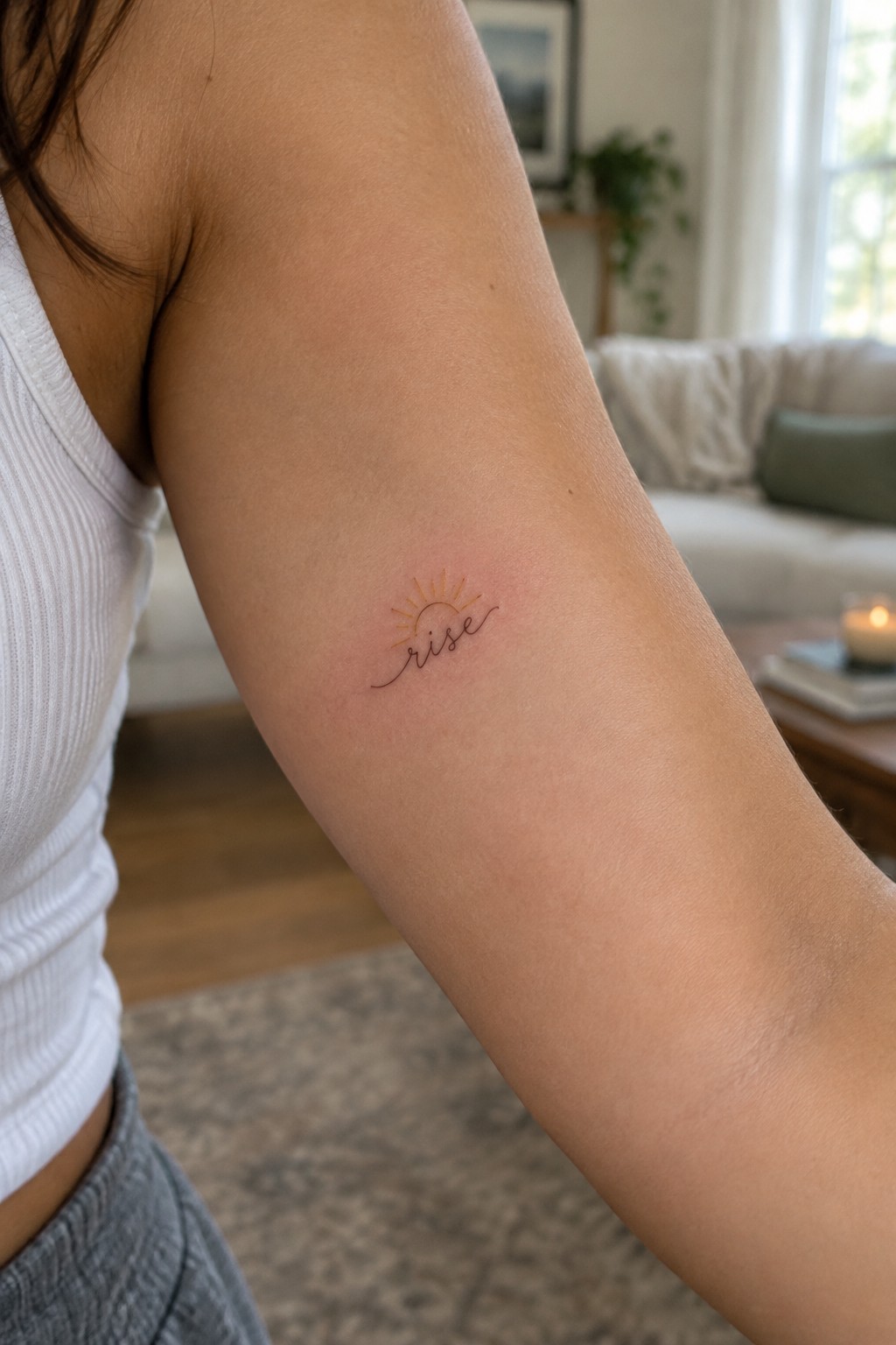 Small fine-line tattoo reading “rise” with golden sun rays on the inner arm.