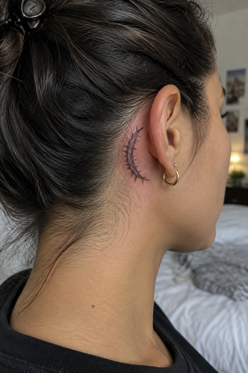 Small black fine line ichthys fish tattoo with skeletal details placed behind the ear on the side of the neck