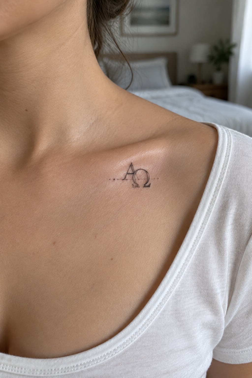 Close-up of light skin shoulder with small black AΩ tattoo above white t-shirt