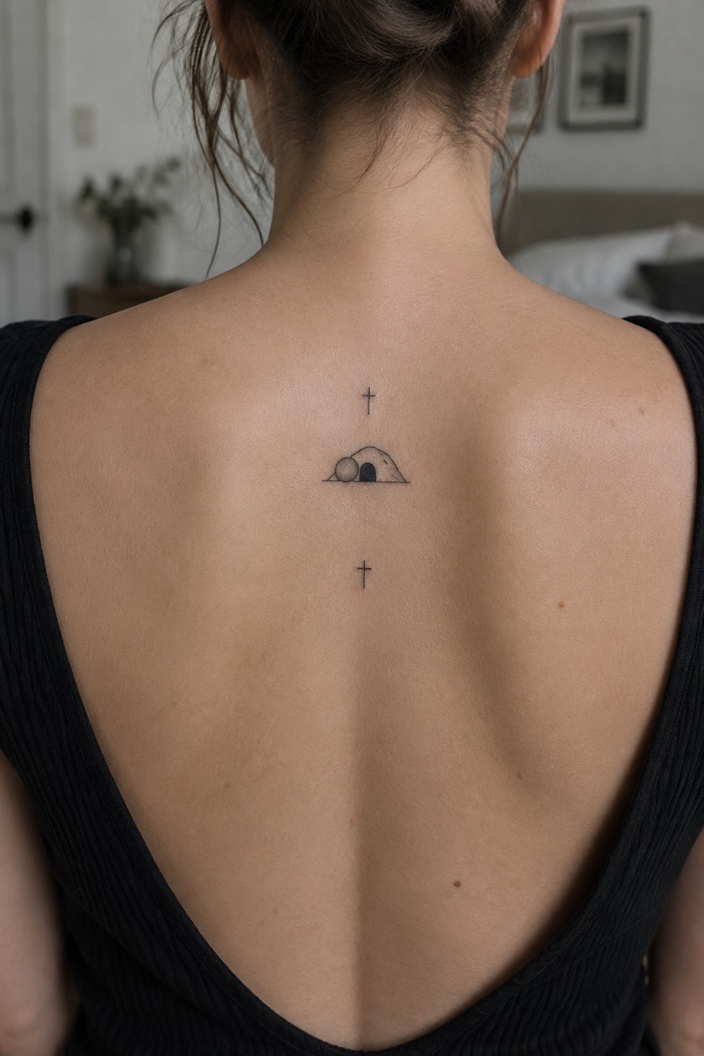 Minimalist line tattoo of an empty tomb with crosses centered on a person's upper back