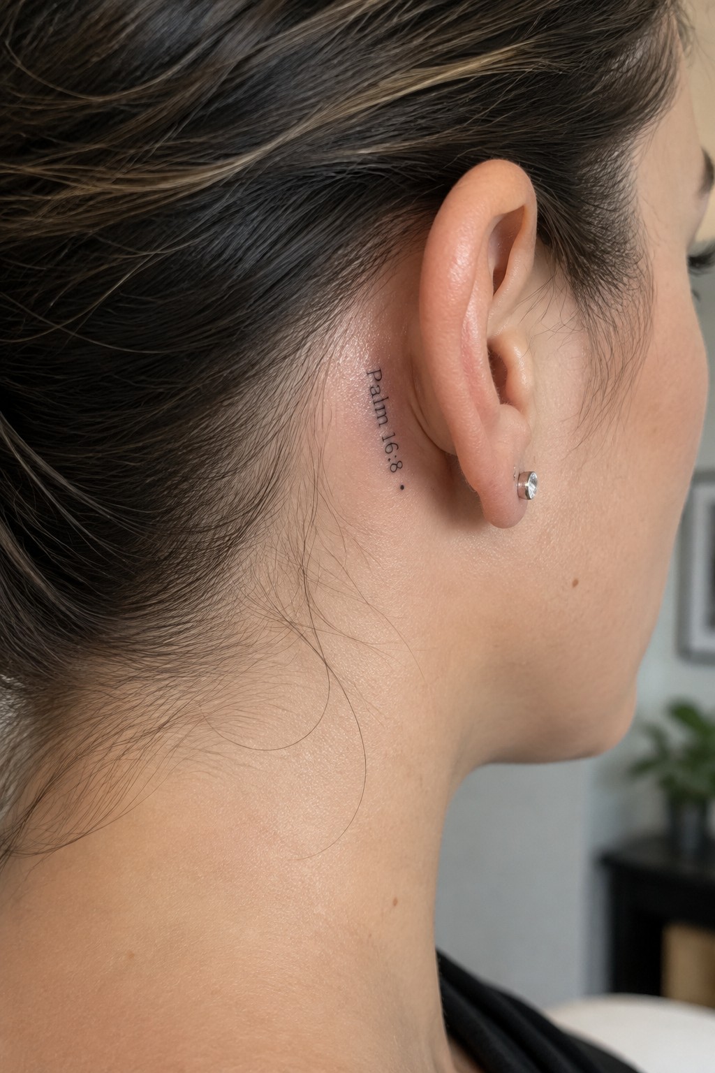 Dark hair pulled back showing Psalm 19:8 tattoo behind ear with stud earring
