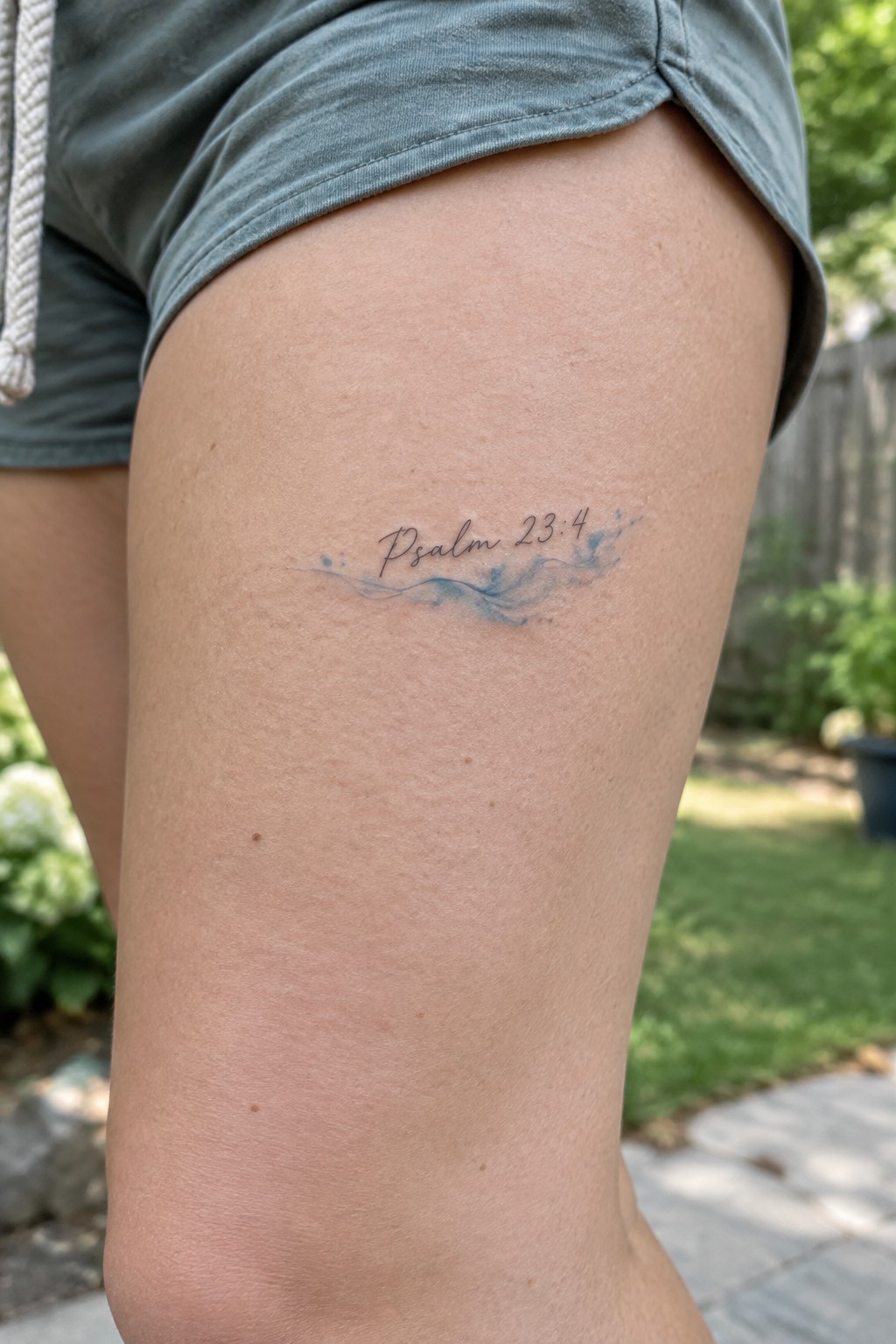 Tattoo on thigh reads Psalm 23:4 in script with blue watercolor wave design