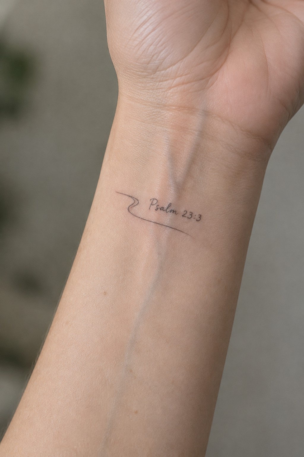 Light-skinned wrist with black script tattoo 