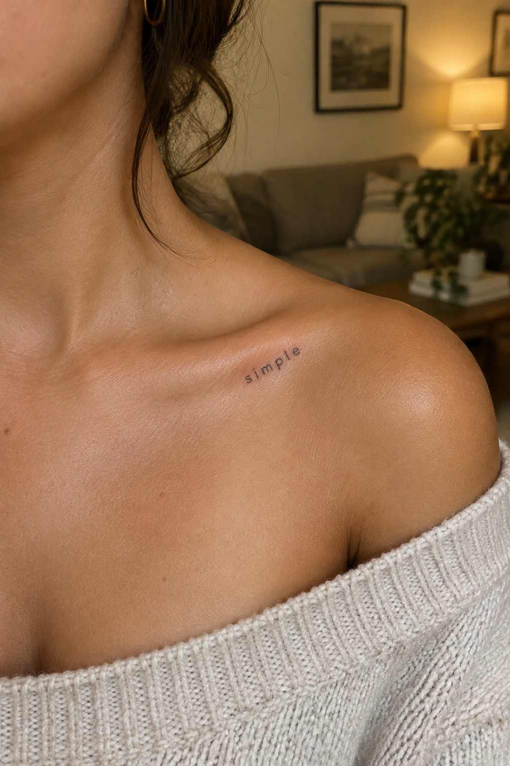 Small lowercase “simple” word tattoo in spaced lettering just below the collarbone.